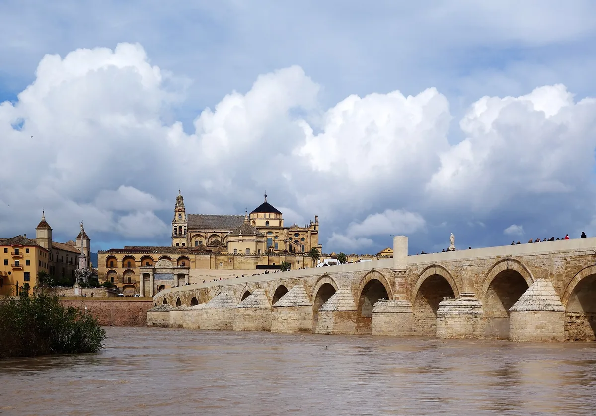 The Roman Bridge over the Guadalquivir leading to the Mosque-Cathedral bell tower at dusk on a mosque cathedral of cordoba tour in Cordoba, Spain